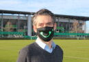 Michael Meeske, Geschäftsführer der VfL Wolfsburg-Fußball GmbH, trägt die Schenke-ein-Lächeln Maske des VfL